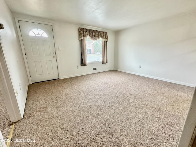 carpeted foyer featuring visible vents and baseboards