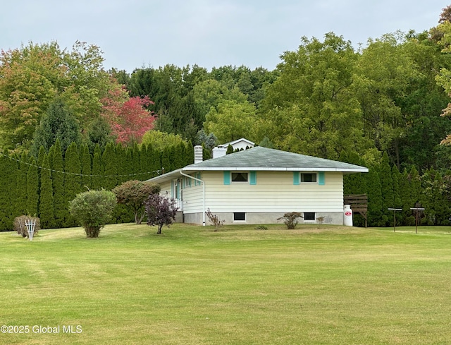 rear view of house featuring a lawn and a view of trees