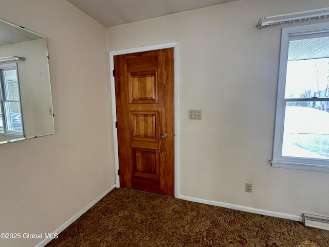 interior space with a baseboard heating unit, a healthy amount of sunlight, baseboards, and carpet floors