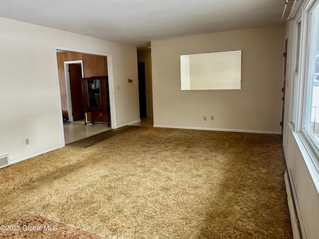 unfurnished room featuring a baseboard heating unit, baseboards, and carpet