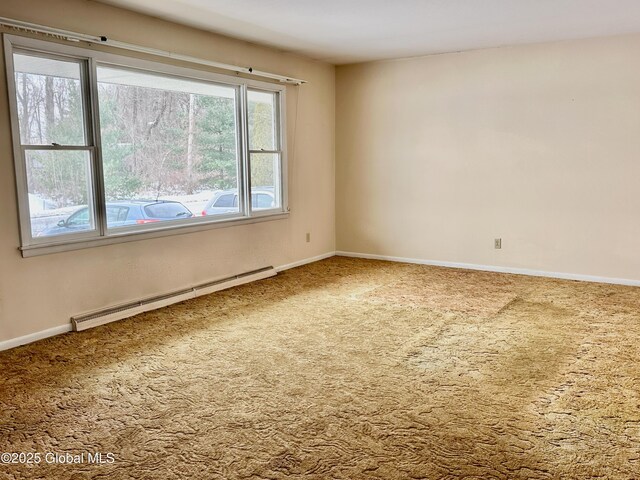 carpeted empty room featuring a baseboard heating unit and baseboards