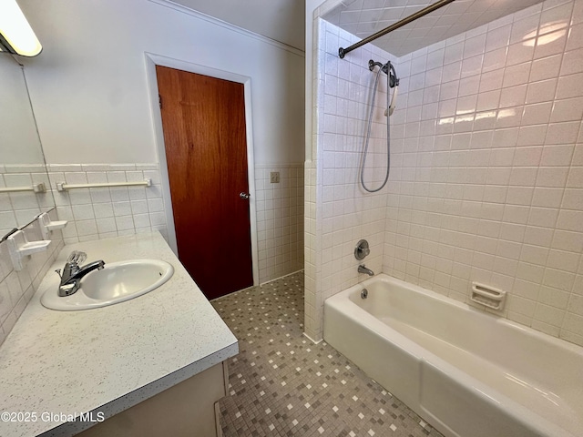 full bath with vanity, tile walls, washtub / shower combination, and wainscoting