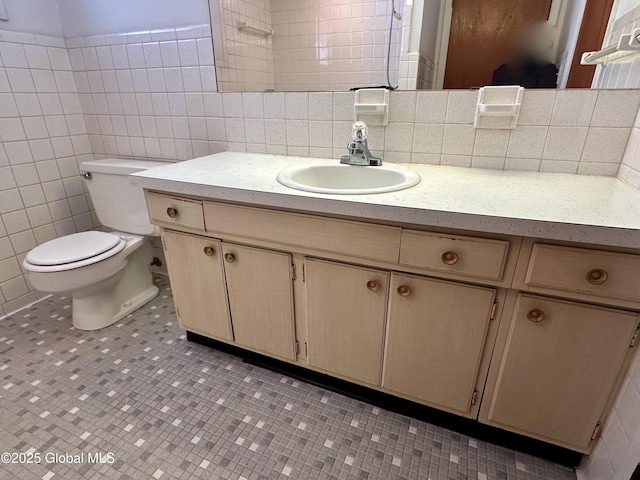 bathroom featuring vanity, tile walls, and toilet