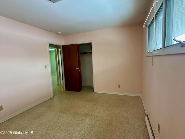 unfurnished bedroom with a closet, baseboards, and a baseboard radiator