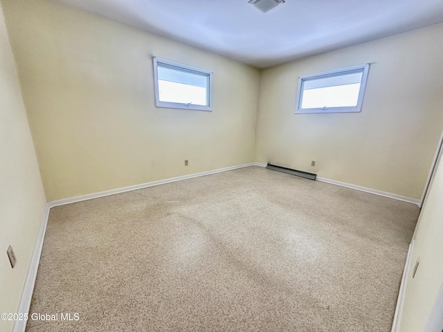 unfurnished room featuring baseboard heating, visible vents, and baseboards