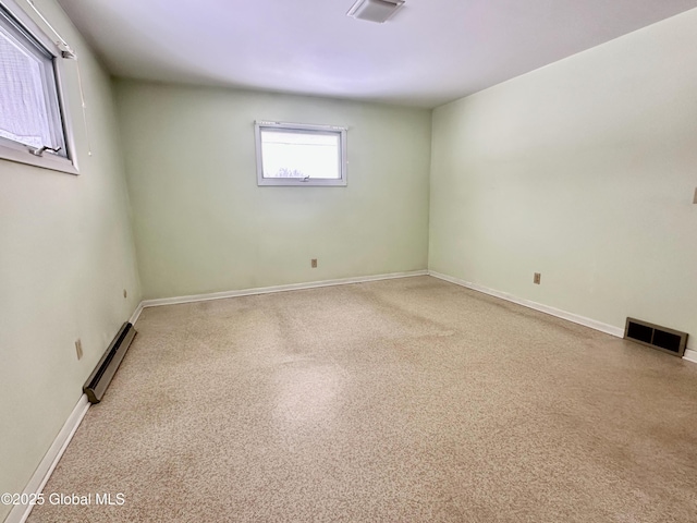 empty room with visible vents, a baseboard heating unit, and baseboards