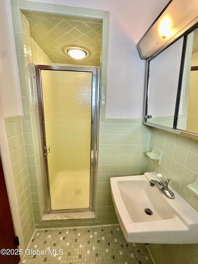 bathroom with a shower stall, tile walls, and a sink