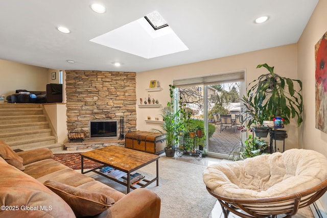 living room featuring a stone fireplace, a skylight, and recessed lighting