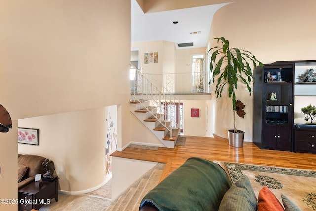 living area with stairway, wood finished floors, and baseboards