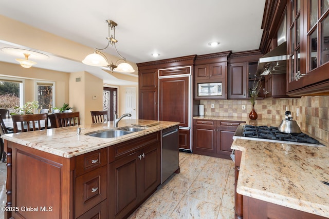 kitchen featuring appliances with stainless steel finishes, a sink, hanging light fixtures, and tasteful backsplash