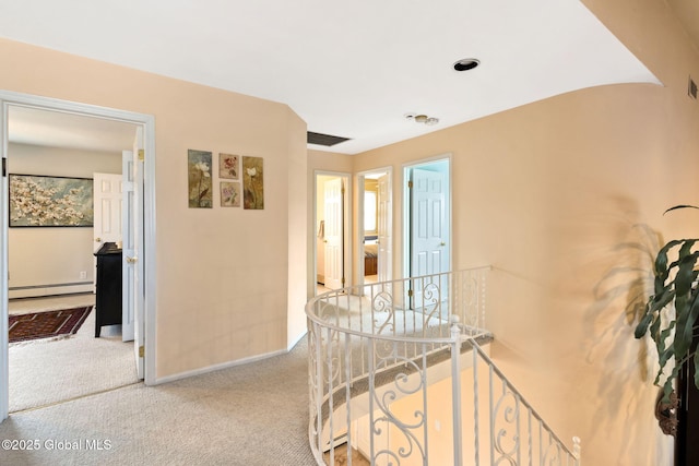 corridor with carpet, baseboards, baseboard heating, and an upstairs landing