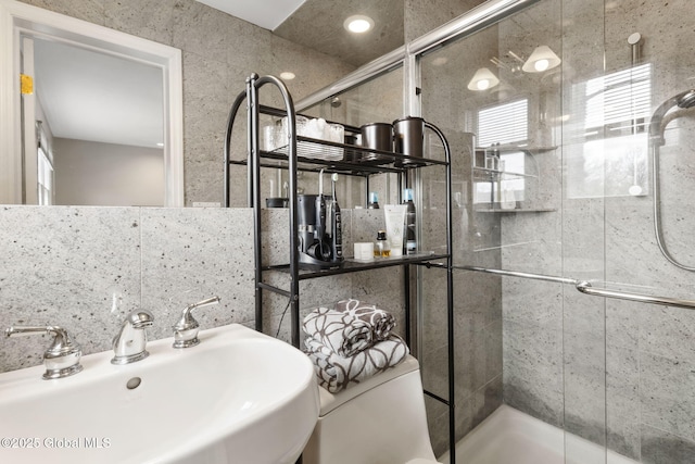 bathroom featuring plenty of natural light, a sink, and a shower stall