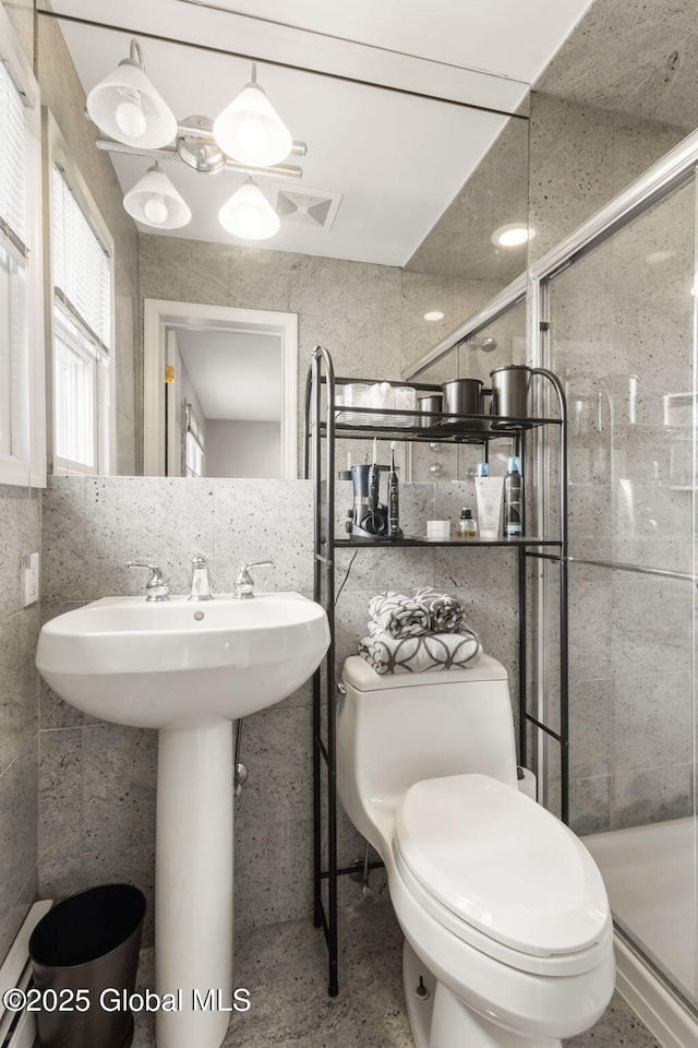 bathroom featuring a stall shower, visible vents, tile walls, and toilet