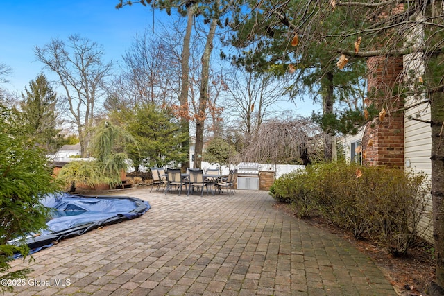 view of patio / terrace with exterior kitchen, outdoor dining area, fence, and a fenced in pool