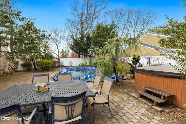 view of patio with a hot tub, a fenced backyard, and outdoor dining area