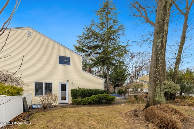 view of side of home featuring fence and a lawn