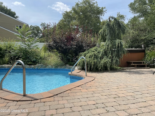 outdoor pool with a patio and a hot tub