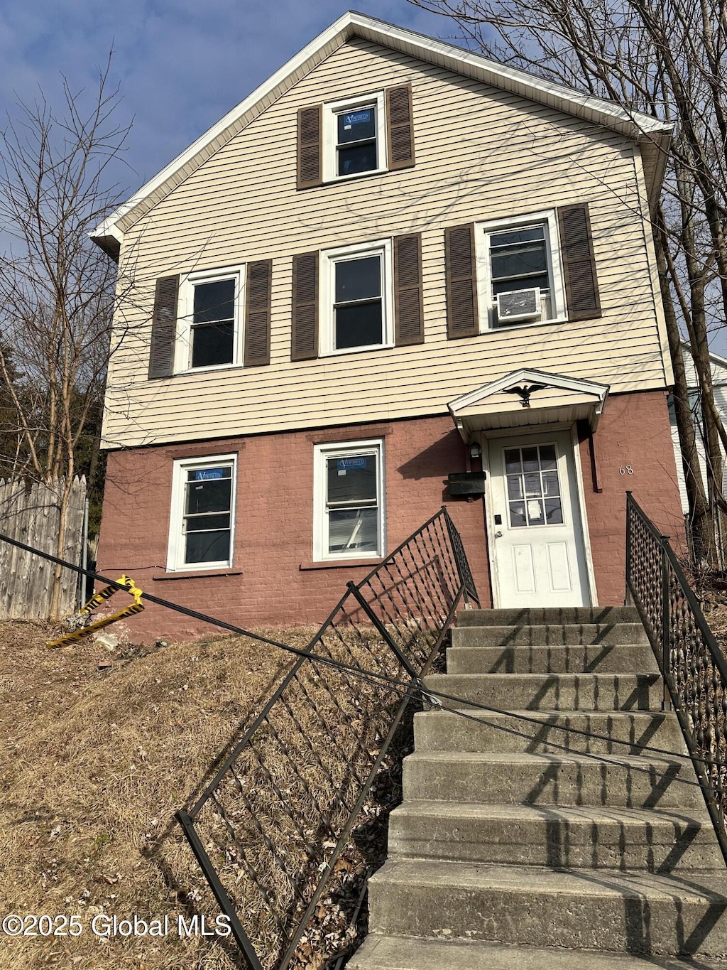 view of front facade featuring brick siding, cooling unit, and fence