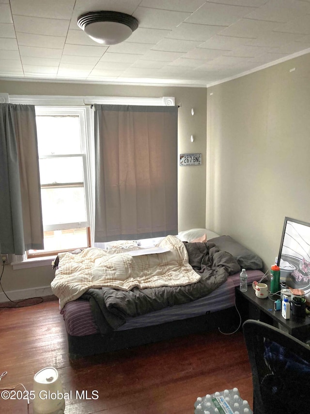 bedroom with ornamental molding and wood finished floors