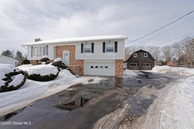 bi-level home with an outbuilding, brick siding, and a detached garage