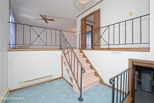 stairs with a baseboard radiator, visible vents, a textured ceiling, and electric water heater