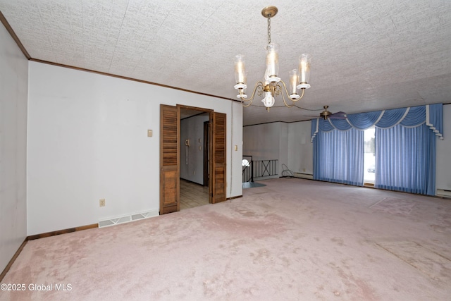 carpeted empty room with ornamental molding, visible vents, a notable chandelier, and baseboards