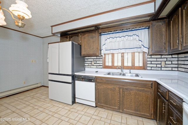 kitchen featuring dark brown cabinetry, white appliances, a sink, light countertops, and wallpapered walls