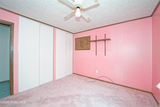 empty room with a textured ceiling, ornamental molding, a ceiling fan, and light colored carpet