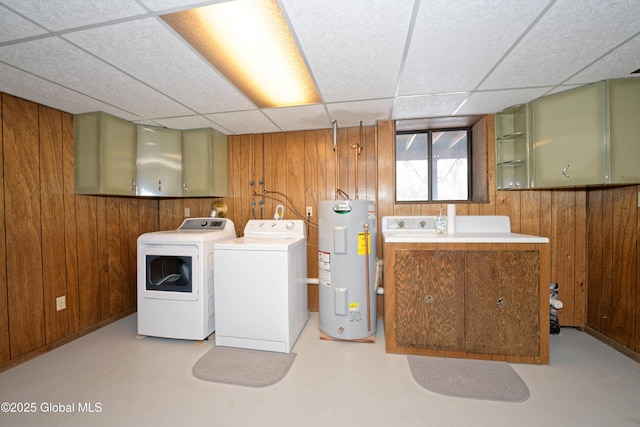 clothes washing area featuring laundry area, washing machine and clothes dryer, electric water heater, and wooden walls