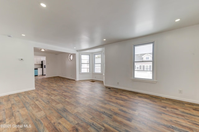 unfurnished living room with baseboards, dark wood finished floors, and recessed lighting