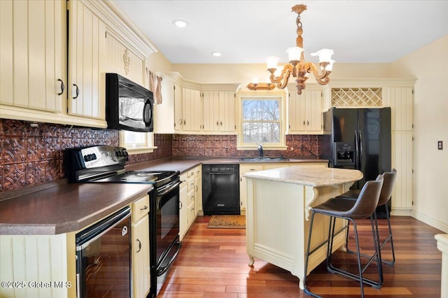 kitchen with wine cooler, a center island, black appliances, pendant lighting, and a sink