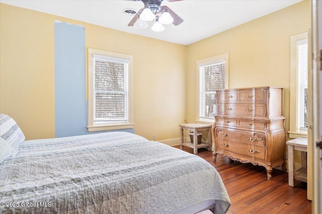 bedroom with dark wood-style floors, a ceiling fan, and baseboards