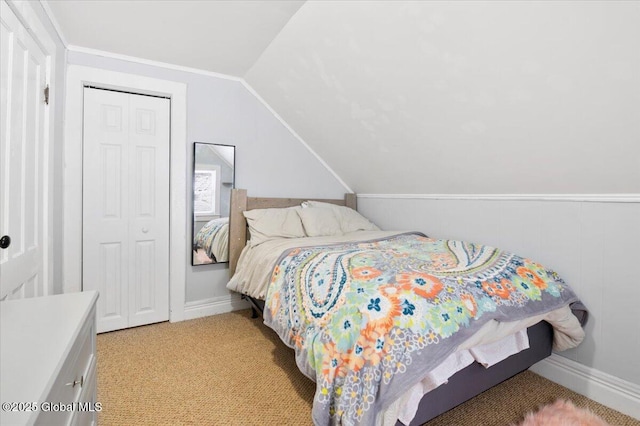 bedroom with vaulted ceiling, a closet, baseboards, and light colored carpet