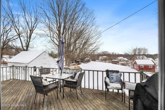 snow covered deck featuring outdoor dining area and grilling area