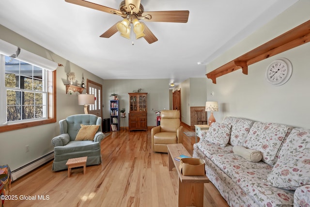 living area with light wood-type flooring, a baseboard radiator, and a ceiling fan