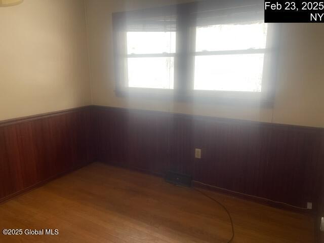 spare room featuring wainscoting, wood walls, and wood finished floors