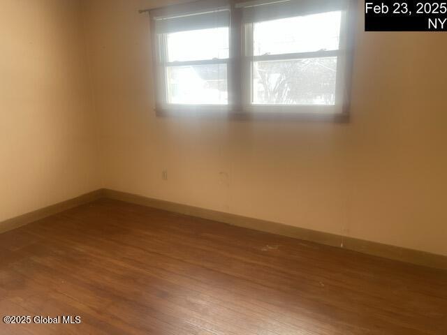 spare room featuring baseboards and wood finished floors