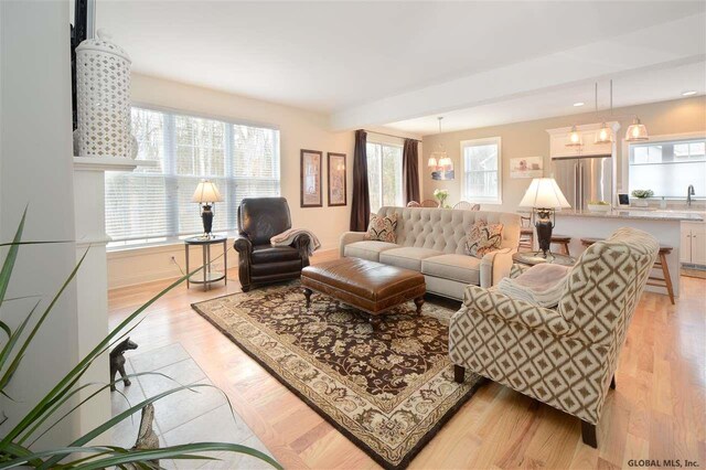 living area with baseboards, light wood-style flooring, and a notable chandelier