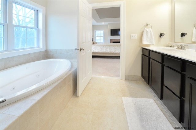 bathroom with ensuite bathroom, tile patterned flooring, a fireplace, vanity, and a jetted tub