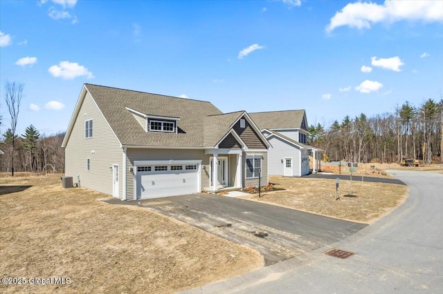 view of front of home featuring central AC, driveway, a garage, and a shingled roof