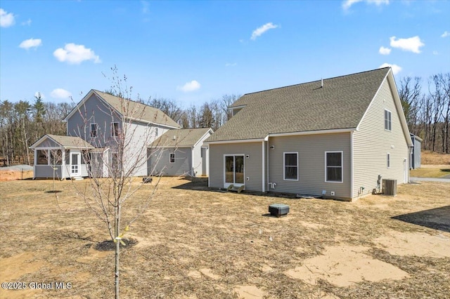 rear view of house with central air condition unit and roof with shingles