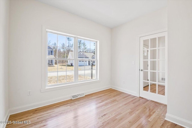spare room featuring baseboards, visible vents, and wood finished floors