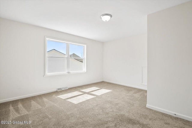 spare room with carpet floors, baseboards, and visible vents