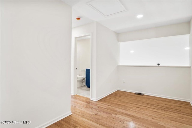 spare room featuring attic access, baseboards, light wood-type flooring, and visible vents