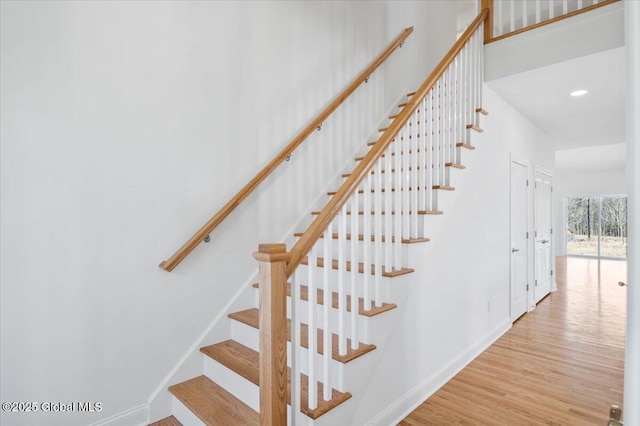 stairway with baseboards, wood finished floors, and recessed lighting