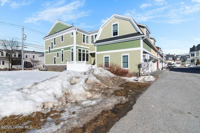 exterior space featuring aphalt driveway, a gambrel roof, and a garage