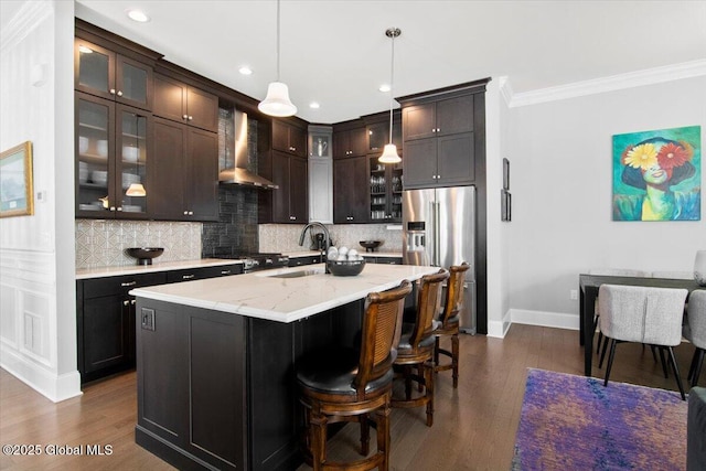 kitchen featuring high end fridge, a sink, backsplash, dark wood finished floors, and wall chimney range hood