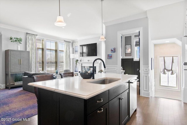 kitchen with dark cabinets, ornamental molding, light countertops, and a sink