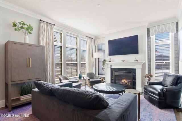 living area with baseboards, a glass covered fireplace, and crown molding