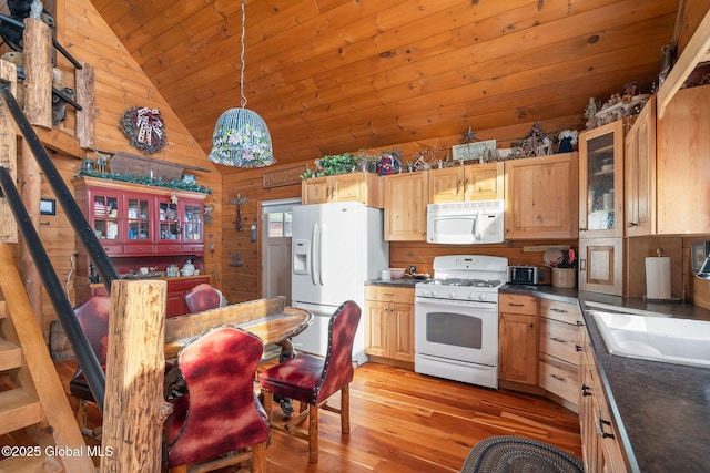 kitchen with white appliances, dark countertops, lofted ceiling, hanging light fixtures, and a sink